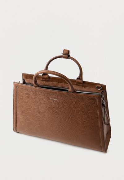 Καφέ δερμάτινη τσάντα με υφή, διπλές λαβές και κλείσιμο με φερμουάρ, τοποθετημένη σε λευκό φόντο.