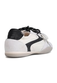 White and black athletic shoe featuring a suede heel, smooth sides, and textured laces. Minimalist design with a rubber sole.