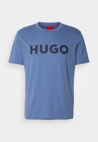 T-shirt bleu à manches courtes et col rond avec le texte "HUGO" en noir centré sur le devant.
