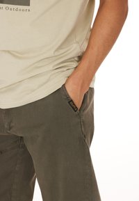 Olivgröna cargobyxor med avslappnad passform, med en sidoficka och en liten loggtagg på midjebandet. Tillverkade av bomull med mjuk textur.