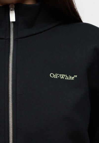 Μαύρο μπουφάν με φερμουάρ κατασκευασμένο από ριμπ ύφασμα, με ασημένιο φερμουάρ και λογότυπο «Off-White» ανοιχτό πράσινο στην αριστερή πλευρά.