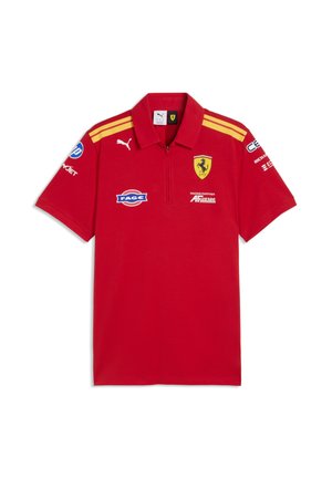 Czerwone polo z krótkim rękawem i żółtymi paskami na ramionach, logo Ferrari na piersi, logo Puma oraz kilka logo sponsorów na przodzie i rękawach.