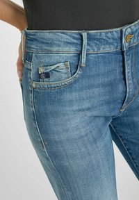 Lichtblauwe denim jeans met een slim fit, subtiele kreukels en een klein merklabel op de voorzak. Klassiek vijf-pocket ontwerp.