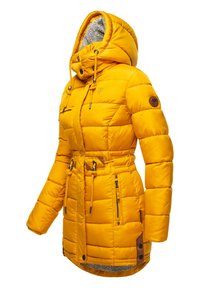 Gul vadderad jacka med en texturerad, fleecefodrad huva, justerbara dragsnören och flera blixtlåsfickor. Bruna läderdetaljer finns.
