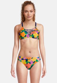 Ensemble de bikini fleuri avec une base sombre et des motifs vifs en rose, jaune et vert. Le haut présente un design croisé avec des bretelles fines.