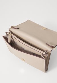 Borsa in pelle beige con texture, chiusura a patta, accessori dorati e due scomparti interni con fodera a motivo.