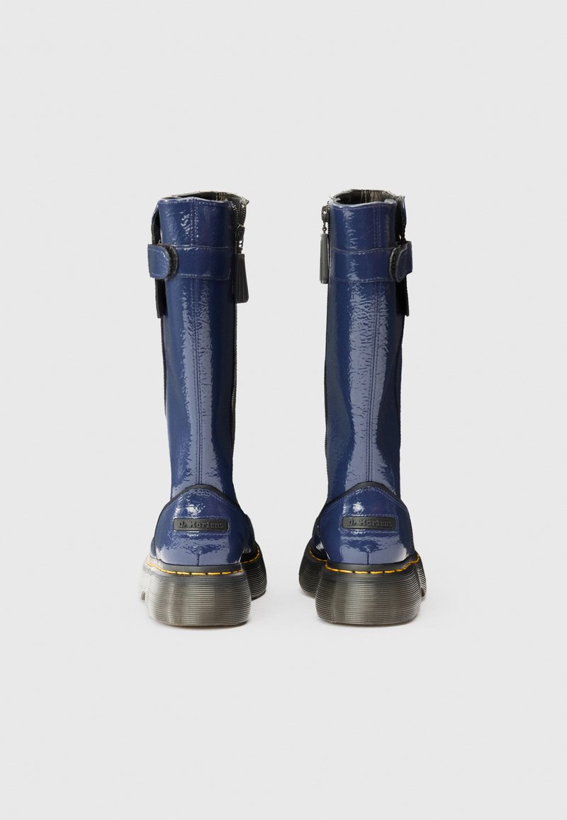 Stivali alte fino al ginocchio in pelle verniciata blu navy con una finitura lucida, tessuto laterale nero, chiusura con zip, cuciture gialle visibili e suole spesse.