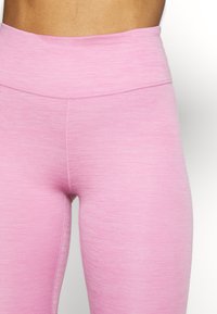Růžové cvičební legíny s vysokým pasem, vyrobené z hladkého, texturovaného materiálu a plochých švů pro maximální pohodlí. Jednoduchý, funkční design.