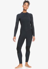 Wetsuit in zwart neopreen met lange mouwen, een hoge kraag en gestructureerde accenten op de schouders; voorzien van kniebeschermers voor extra bescherming.