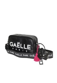 Borsa a tracolla rettangolare nera con logo bianco GAËLLE PARIS, tracolla regolabile con brand e portachiavi con pon-pon rosa attaccato alla cerniera.