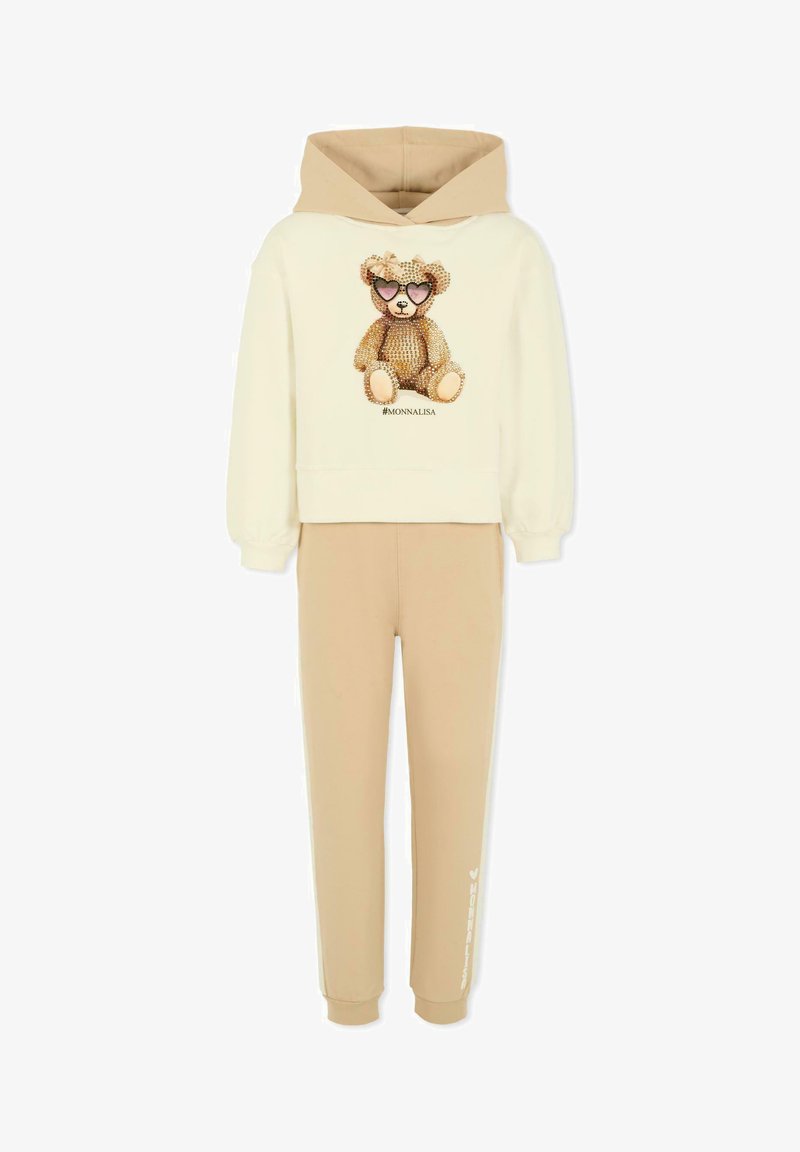 Beige katoenen hoodie en broek set. De hoodie heeft een teddybeer graphic met zonnebril en sprankels. Zacht materiaal met geribbelde boorden.