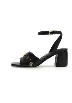 Schwarze offene Sandale mit Blockabsatz, Knöchelriemen mit goldener Schnalle und dekorativen goldenen Nieten am Vorderriemen.