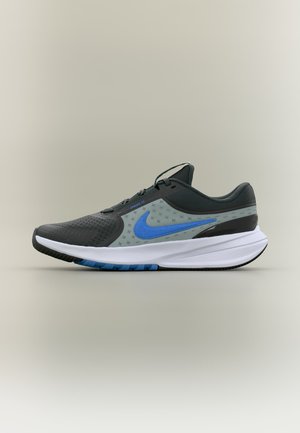 Chaussure de course noire et grise avec le swoosh Nike bleu, semelle intermédiaire blanche et tige en mesh respirant, vue de côté sur fond neutre.