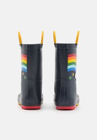 Granatowe kalosze z gumy w tęczowy wzór, z żółtymi uchwytami, czerwonymi podeszwami i zielonymi gwiazdkami, z tylnym i bocznym wzorem.