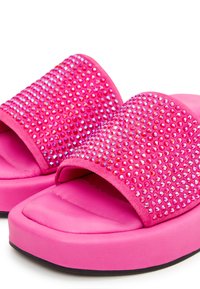 Leuchtend pinke Plateausandalen mit gepolsterten Sohlen und breiten Riemen, die mit kleinen schimmernden Strasssteinen verziert sind.