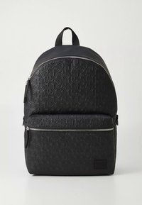 Must seljakott, millel on reljeefne "HUGO" logo. Omab kumerat pealiskülge, esiküljel lukuga taskut ja reguleeritavaid õlarihme. Valmistatud vastupidavast materjalist.