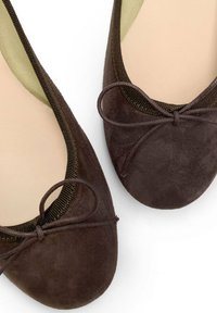 Bailarinas de ante marrón con puntera redonda, con un lazo decorativo y un borde elástico en contraste a lo largo de la apertura. Forro interior suave.