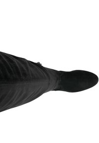 Czarne zamszowe kozaki za kolano o dopasowanym kroju, zwężającym się czubku i płaskiej podeszwie. Gładka faktura i minimalne elementy metalowe.