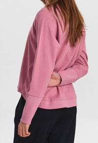 Rosa Sweatshirt mit langen Ärmeln, gerippten Bündchen und Saum. Weicher Stoff mit lockerer Passform, von hinten gezeigt.