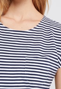 Marineblau-weiß gestreites T-Shirt mit rundem Ausschnitt und kurzen Ärmeln; verfügt über eine kleine Brusttasche und eine weiche, glatte Stoffoberfläche.