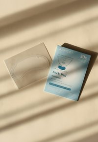 Coussin de cou en gel transparent sur un support en plastique flexible, à côté d'un emballage bleu étiqueté "APRICO" avec les détails et instructions du produit.