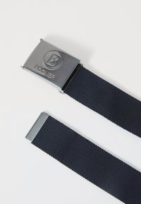 Ceinture en tissu tressé bleu marine avec une boucle rectangulaire en argent brillant ornée d'un logo en relief. La boucle présente une texture métallique lisse.