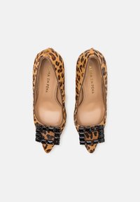 Tacones pico con estampado de leopardo y textura suave, con un adorno decorativo negro en la punta. Interior color beige claro.