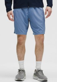 Lyseblå sportsshorts med elastisk talje. Båret med grå sneakers og hvide sokker. Glat, letvægtsstof med en afslappet pasform.