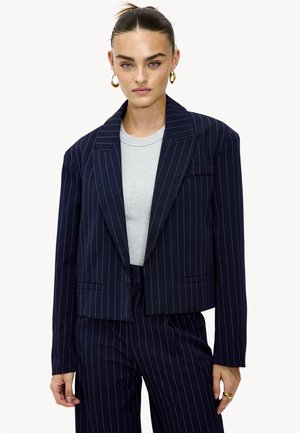 Blazer court à rayures navy en tissu léger, avec un col cranté, une poche avant simple et des accents subtils en métal doré.