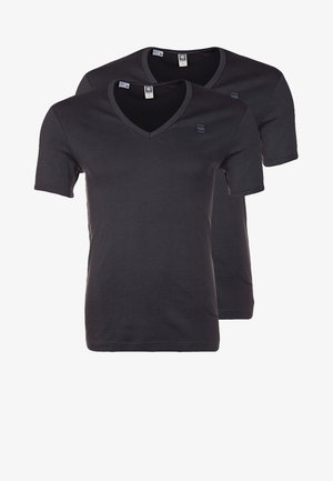 Zwei schlichte schwarze T-Shirts mit V-Ausschnitt und kurzen Ärmeln, gestapelt, jeweils mit kleinem Logo auf der linken Brust und Größenschildern sichtbar im Halsausschnitt.