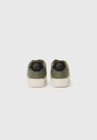 Baskets en toile vertes avec une semelle blanche, dotées d'un talon en cuir noir comportant le logo "Nike Air" et des détails de couture subtils.