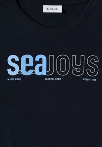 T-shirt en coton marine avec le texte "seaJoys" en bleu clair et gris, accompagné des phrases "MAGIC HOUR", "COASTAL CALM" et "FRESH TIDES" en dessous.