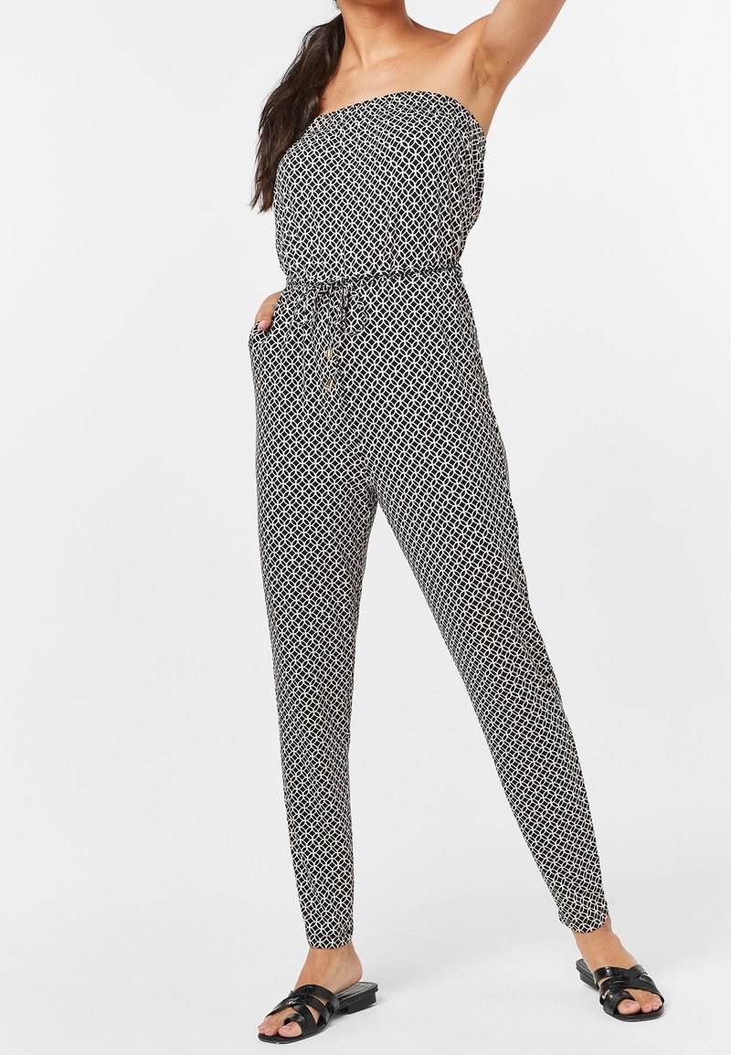 Combinaison à motifs noir et blanc avec un design sans bretelles, taille élastique et jambes fuselées. Comprend des poches latérales et un tissu léger.