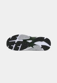 Footwear with a textured black rubber sole, grey and white accents, and a green center section featuring a patterned tread design.