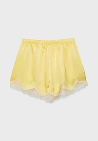 Shorts pour femmes en satin jaune avec taille élastique et bordure en dentelle blanche le long de l'ourlet festonné.