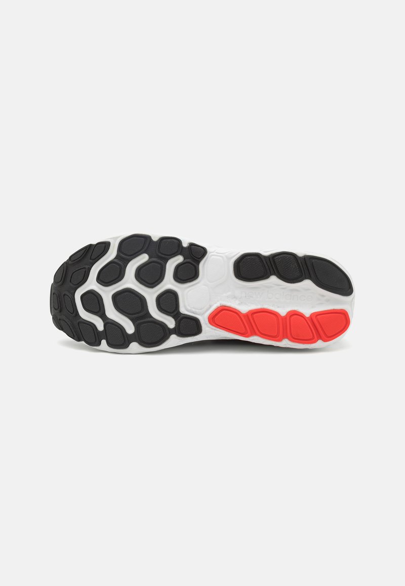 Sohle eines Laufschuhs mit schwarzen und roten Gummiprofilmustern auf einem weißen Grund, die eine strukturierte Griffigkeit und ein flexibles Design zeigt.