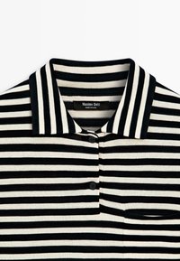Polo à rayures horizontales noires et blanches avec un col, deux boutons noirs et une petite poche poitrine, étiqueté Massimo Dutti.