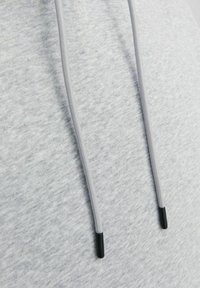 Gray hoodie fabric with a textured appearance, featuring drawstrings and black tips for adjustment.