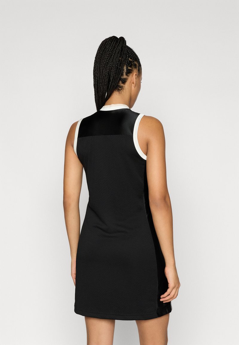 Robe noire sans manches en tissu texturé avec un col lisse ; comprend des accents blancs au niveau de l'encolure et du dos.