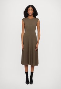 Olive green ribbed knit dress with cap sleeves, fitted bodice, and flared skirt. Worn with black ankle boots and socks.