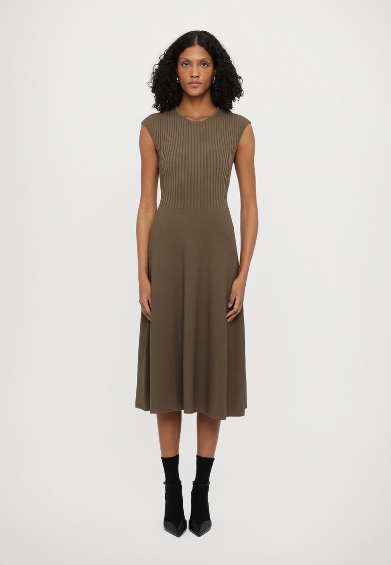 Olive green ribbed knit dress with cap sleeves, fitted bodice, and flared skirt. Worn with black ankle boots and socks.