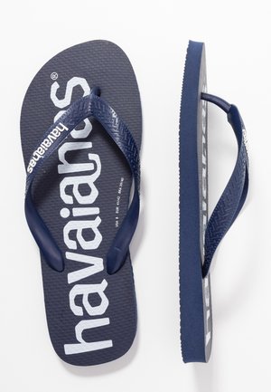 Granatowe japonki Havaianas z białym napisem logo, teksturowanymi paskami i gumowymi podeszwami, widoczne z góry i z boku.