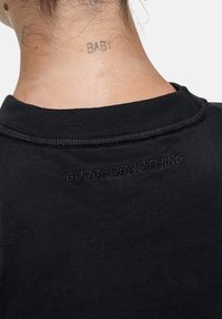 T-shirt in cotone nero con collo a giro, con la scritta "GOODFORNOTHING" ricamata in nero sul retro vicino al collo.