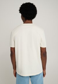 Short-sleeve, crew-neck t-shirt in off-white cotton. Smooth texture, relaxed fit, straight hem. Minimal design without patterns or accents.