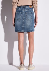 Džínová sukně v světle modré barvě se střihem do rovna, pěti kapsami a jemným odřením. Má pevný pas a zadní lem, který sahá nad koleno.