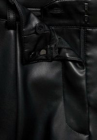 Black leather pants featuring a smooth texture, button detail at the waistband, and a side pocket with visible stitching. Zipper closure included.