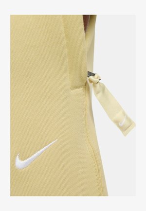 Top sportivo giallo chiaro con tessuto testurizzato, dotato di logo Nike bianco e laccio laterale regolabile per una vestibilità ottimale.