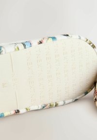 Semelle d'une pantoufle avec le texte embossé "INEXTENSO" et une bordure en tissu multicolore sur un fond clair.