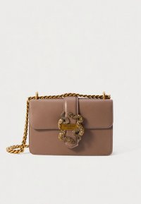 Borsa a mano in pelle marrone con tracolla in catena dorata intrecciata e chiusura decorativa a forma di serpente su sfondo bianco semplice.