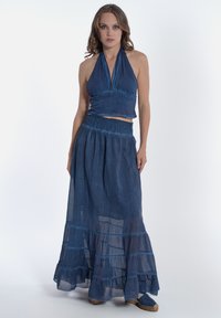 Set in denim composto da top a halter e gonna maxi. La gonna presenta volants sovrapposti ed è realizzata in un tessuto leggero e testurizzato.